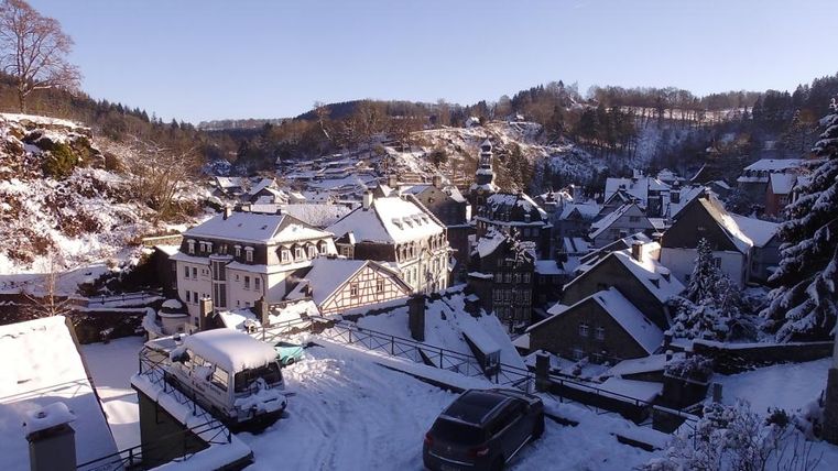 Eine verschneite Stadtansicht mit traditionellen Häusern und verschneiten Dachlandschaften. Der Himmel ist klar und strahlend blau.