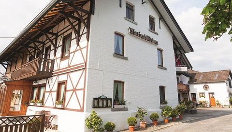 Ein charmantes Fachwerkhaus mit einem einladenden Eingang. Die Fassade ist weiß mit holzverzierten Elementen und dekorativen Pflanzen.