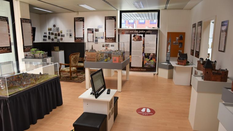 Ein Museum mit verschiedenen Exponaten und Informationen zur Geschichte. Es gibt Modelle und Ausstellungen, die in einem hellen Raum präsentiert werden.