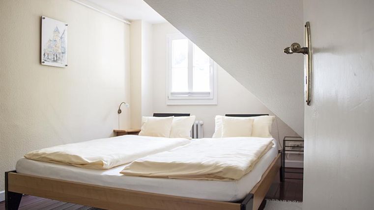 Ein gemütliches Schlafzimmer mit einem Doppelbett und zwei Kissen. Ein Fenster sorgt für viel Tageslicht.
