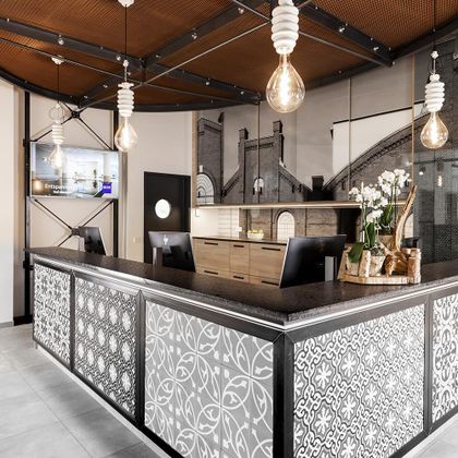 Eine moderne Empfangstheke mit eleganter Dekoration und warmem Licht. Im Hintergrund befinden sich ein Fernseher und eine stilvolle Innenarchitektur.