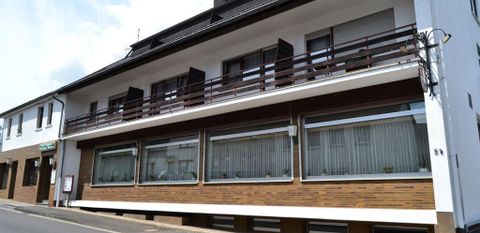 Ein modernes Gebäude mit mehreren Etagen und großen Fenstern. Die Fassade ist mit braunen Ziegeln verkleidet und es gibt Balkone im oberen Bereich.