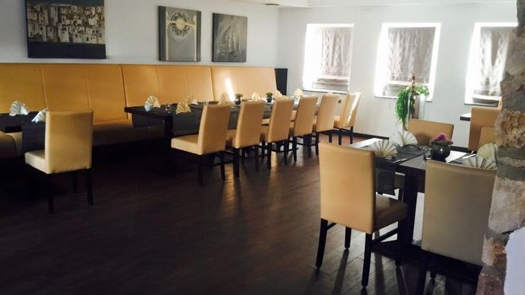 Ein elegantes Restaurant mit Holzfußboden. Gemütliche Tische und Stühle sind umgeben von sanften Farben und Kunstwerken an den Wänden.