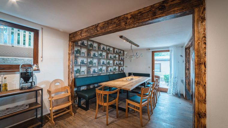 Ein gemütlicher Essbereich mit einem großen Holztisch und Holzstühlen. An der Wand sind zahlreiche Bilder zu sehen, die eine einladende Atmosphäre schaffen.