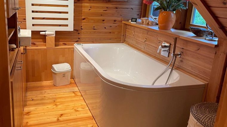 Ein stilvolles Badezimmer mit einer modernen Badewanne und Holzwänden. Es gibt auch eine Pflanze auf der Fensterbank und einen Handtuchheizkörper.