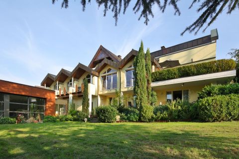 Ein modernes Haus mit einem gepflegten Garten und großen Fenstern. Die Architektur ist ansprechend und kombiniert Holz- und Glaselemente.