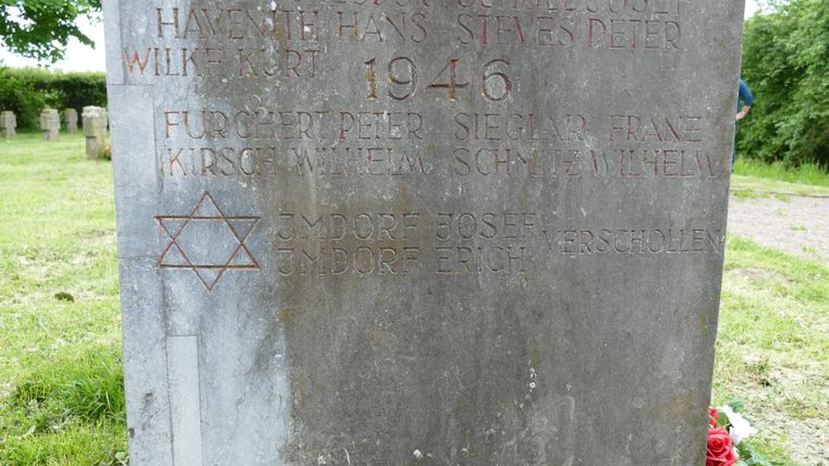 Ein Gedenkstein aus Stein mit Inschriften aus dem Jahr 1946. Der Stern David ist sichtbar, um an den Holocaust zu erinnern.