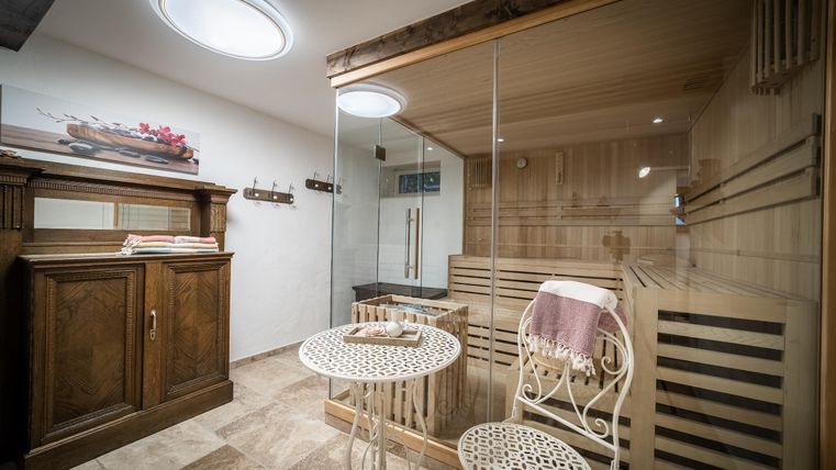Ein eleganter Wellnessbereich mit einer Sauna und einem kleinen Tisch. Der Raum ist modern und gut beleuchtet, ideal zum Entspannen.
