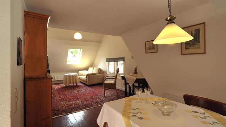 Eine gemütliche Wohnung mit einem Essbereich und einem Wohnbereich. Der Raum hat warme Farben und viel Tageslicht.