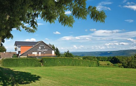 Ein malerisches Hotel auf einer Wiese mit wunderschönem Blick auf die Hügel. Der klare blaue Himmel und die grünen Landschaften schaffen eine friedliche Atmosphäre.