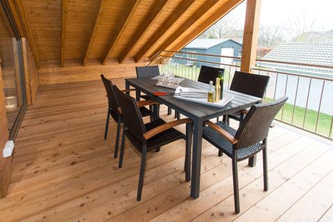 Ein schöner Essbereich auf einer Veranda mit einem Tisch und sechs Stühlen. Die Holzböden und die offenen Fenster schaffen eine einladende Atmosphäre.
