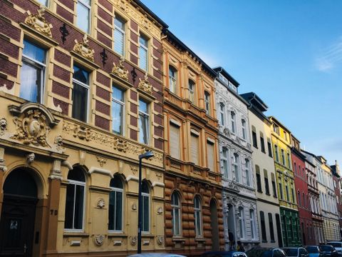 Eine Reihe farbenfroher Gebäude entlang einer Straße. Die Fassaden zeigen unterschiedliche architektonische Stile und Farben.