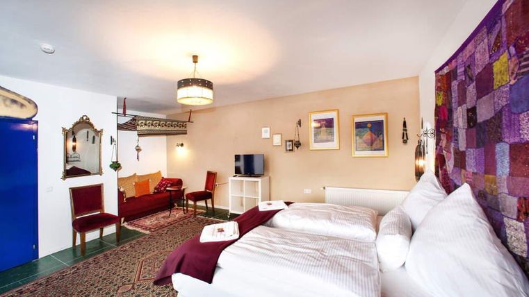 Ein gemütliches Zimmer mit einem großen Bett und einem Sitzbereich. Die Wände sind farbenfroh dekoriert, und es gibt einen Teppich auf dem Boden.