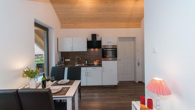 Moderne Küche mit eleganter Einrichtung und Holzdecke. Ein einladender Essbereich mit Tisch und Stühlen.