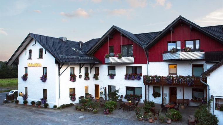 Ein charmantes Gasthaus mit rot-weißer Fassade und blühenden Blumen. Der Außenbereich lädt zum Entspannen ein.