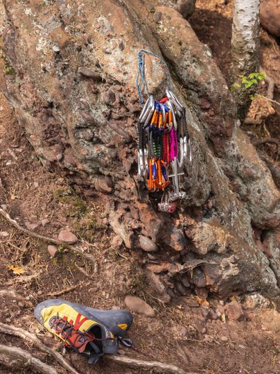 Ein Klettergelände mit einem Felsen und einer Kletterausrüstung. Ein Kletterschuh liegt daneben.