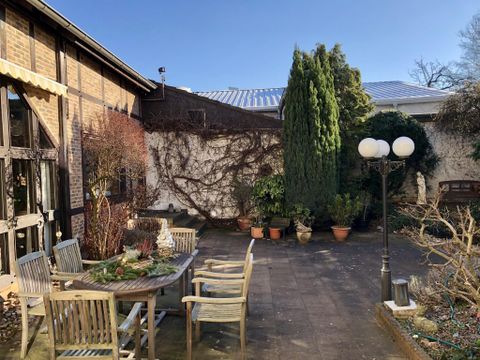 Ein schöner Garten mit einem Tisch und Stühlen. Im Hintergrund sind grüne Pflanzen und ein blauer Himmel zu sehen.
