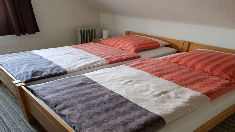 Ein gemütliches Zimmer mit zwei Einzelbetten. Die Bettwäsche ist in warmen Farben gehalten und sorgt für eine einladende Atmosphäre.