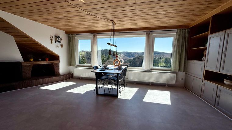 Ein helles Zimmer mit Holzdecke und großen Fenstern. Der Blick auf die Landschaft ist wunderschön.