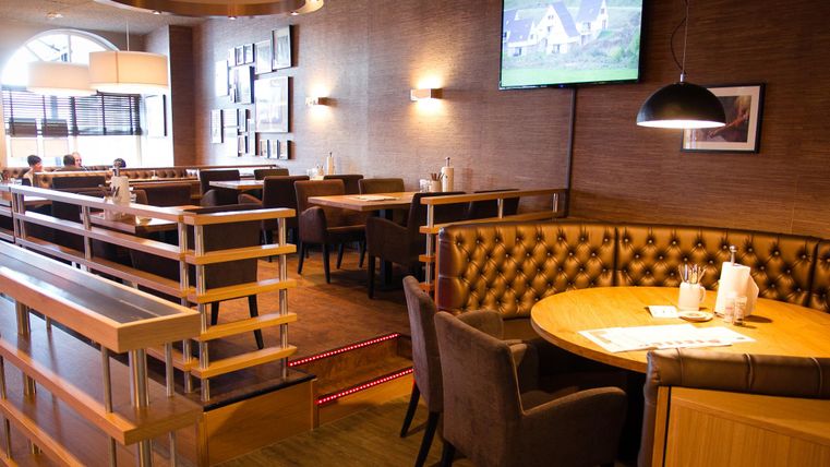 Ein gemütliches Restaurant mit einem modernen Interieur. Die Sitzgelegenheiten sind bequem, und es gibt einen Fernseher an der Wand.