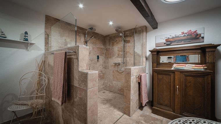 Ein modernes Badezimmer mit einer doppelt offenen Dusche und stilvollen Fliesen. Holz- und Metallakzente verleihen dem Raum eine gemütliche Atmosphäre.