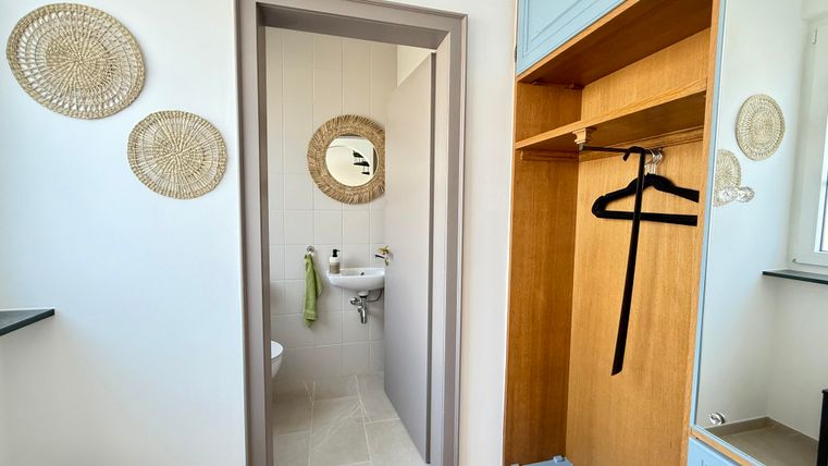 Ein heller Eingangsbereich mit einer Garderobe und einem Spiegel. An der Wand hängen dekorative Wandschalen.