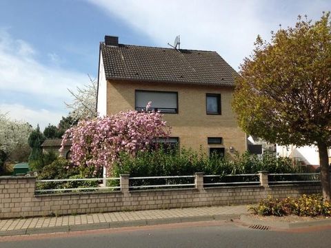 Ein schönes Haus mit einem großen Garten und blühenden Kirschbäumen. Der Himmel ist klar und die Umgebung ist grün.
