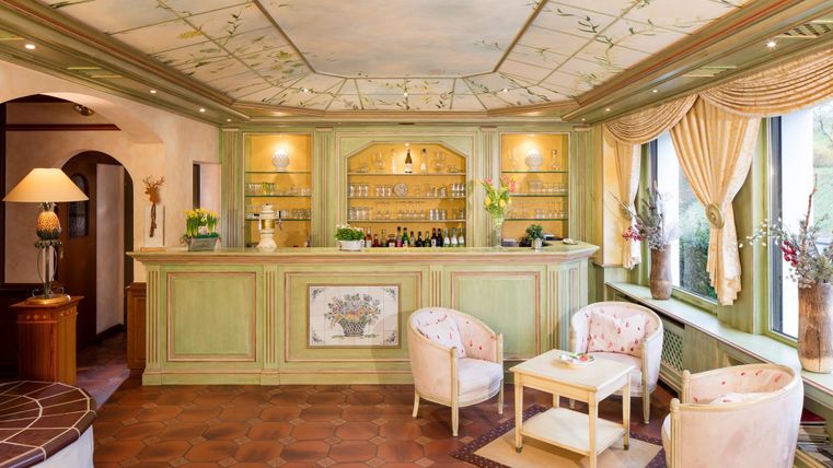 Ein einladender Empfangsbereich mit einer grünen Bar und eleganten Sitzgelegenheiten. Der Raum ist hell und geschmackvoll dekoriert.