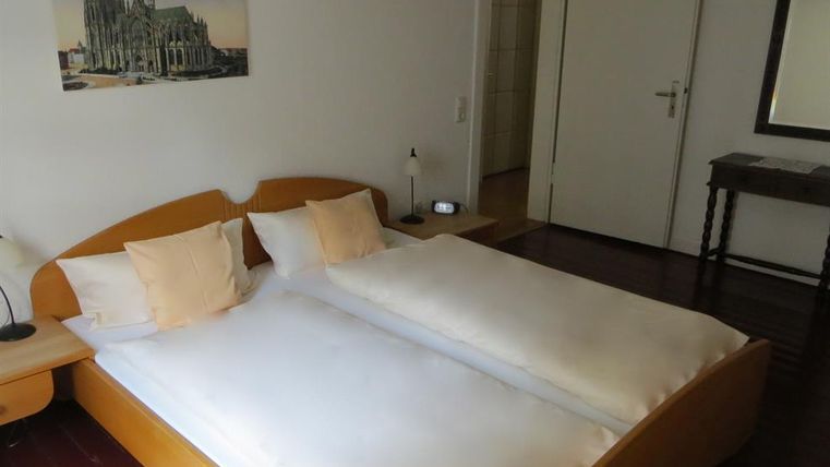 Ein gemütliches Schlafzimmer mit einem Doppelbett und zwei Kissen. An der Wand hängt ein Bild einer schönen Kathedrale.