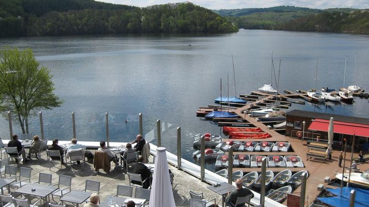 Ein ruhiger See mit Bootsanleger und vielen Freizeitbooten. Die Umgebung ist grün und die Atmosphäre ist entspannend.