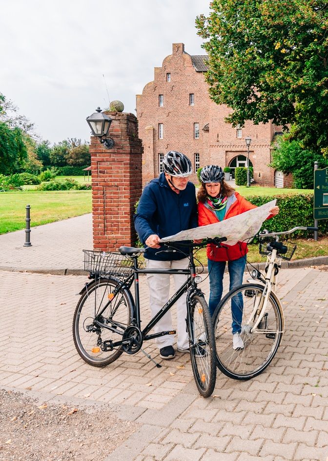 Radfahrende mit Karte auf der Wasserburgen-Route vor Burg Obbendorf