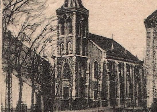 Eine alte Kirche mit einem hohen Turm und Bäumen im Vordergrund. Die Architektur ist schlicht und aus Stein gebaut.