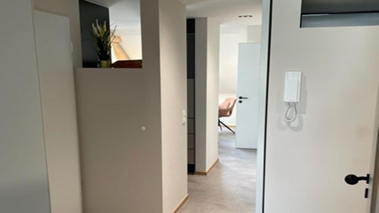 Ein moderner Flur mit hellen Wänden und sanften Farben. Die offene Raumgestaltung vermittelt eine einladende Atmosphäre.