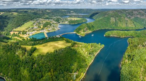 Eine luftige Aussicht auf eine wunderschöne Landschaft mit Flüssen und sanften Hügeln. Grüne Wälder umgeben die Gewässer und das kleine Dorf am Ufer.
