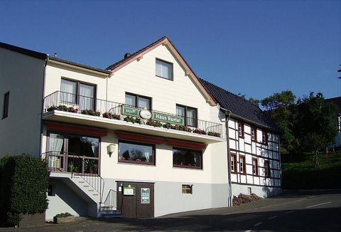 Ein charmantes Gebäude mit einem begrünten Eingangsbereich. Die Fassade ist freundlich und einladend, mit Blumen auf dem Balkon.