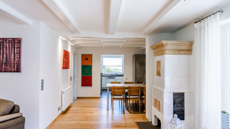 Ein modernes, helles Wohnzimmer mit Holzfußboden und einem Kamin. Der Raum ist mit Kunstwerken und einem Esstisch dekoriert.