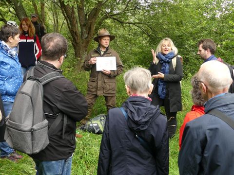 Eine Gruppe von Menschen, die etwas von einem Ranger erklärt und gezeigt bekommen. Dies wird von einer Gebärdendolmetscherin übersetzt.