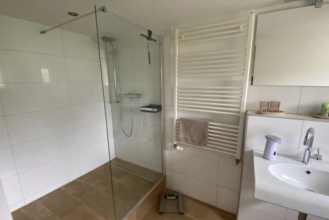 Ein modernes Badezimmer mit einer gläsernen Dusche und einer eleganten Waschbeckenarmatur. Die Wände sind in hellen, neutralen Farben gefliest.