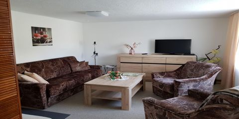 Ein gemütliches Wohnzimmer mit braunen Sofas und einem Holzkaffee Tisch. An der Wand hängt ein Bild, und ein Fernseher steht auf der Kommode.