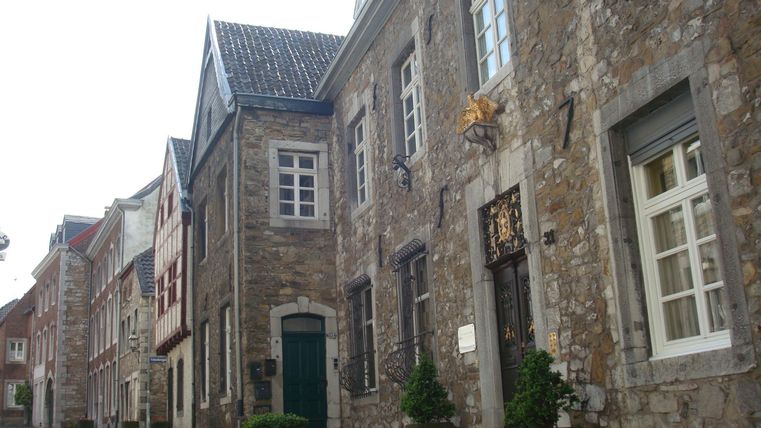 Eine malerische Straße mit historischen Steinmauern und charmanten Fenstern. Die gepflasterte Straße lädt zum Flanieren ein.