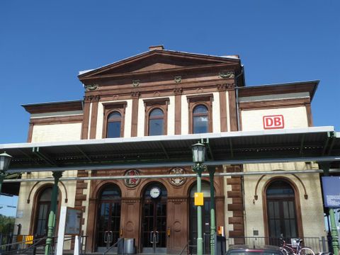 Ein historisches Bahnhofsgebäude mit einer eleganten Fassade. Die Zeit zeigt 12:00 Uhr auf der Wanduhr.