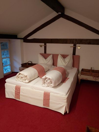 Ein gemütliches Schlafzimmer mit einem großen Bett und frischen Handtüchern. Die Wände sind in sanften Farben gehalten, und der Boden ist mit rotem Teppich ausgelegt.