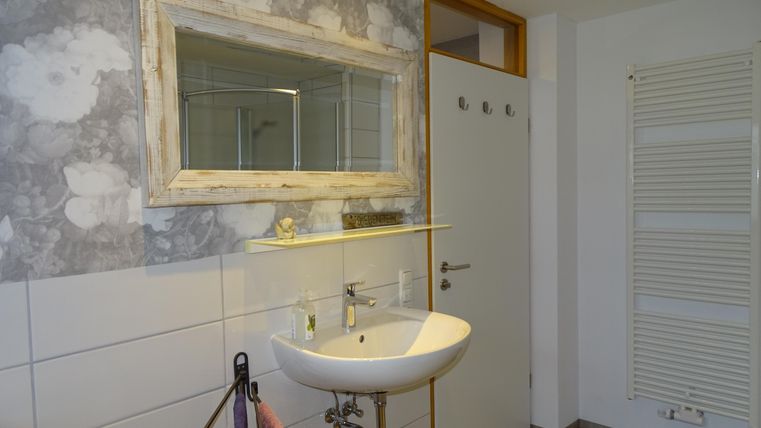 Ein modernes Badezimmer mit einem Waschbecken und einem großen Spiegel. Die Wände sind dekoriert mit einem stilvollen, grauen Muster.