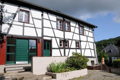 Ein modernes Fachwerkhaus mit grünen Türen und Fenstern. Der Eingangsbereich ist von einer gepflegten Gartenlandschaft umgeben.