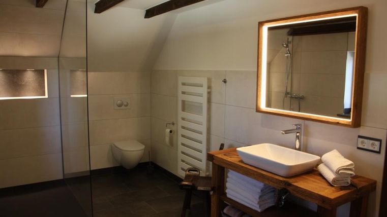 Ein modernes Badezimmer mit einer gläsernen Dusche und einem eleganten Waschbecken. Holz- und Fliesenelemente sorgen für eine einladende Atmosphäre.