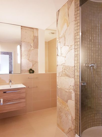 Ein modernes Badezimmer mit einer Dusche und stilvollen Steinfliesen. Der Raum ist hell und minimalistisch gestaltet.