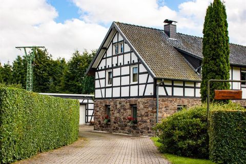 Ein charmantes Fachwerkhaus mit einem gepflasterten Weg. Umgeben von grünen Hecken und einem schönen Garten.
