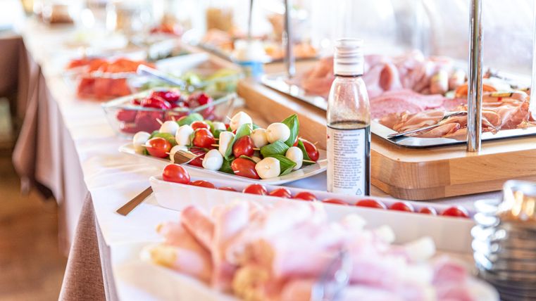 Ein Buffet mit verschiedenen frischen Lebensmitteln, darunter Gemüse, Aufschnitt und Snacks. Die Tische sind ordentlich gedeckt und einladend.