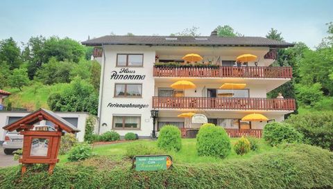 Ein gemütliches Haus mit dem Namen "Panoorama", das Ferienwohnungen anbietet. Die Fassade ist von grünen Büschen und gelben Sonnenschirmen umgeben.
