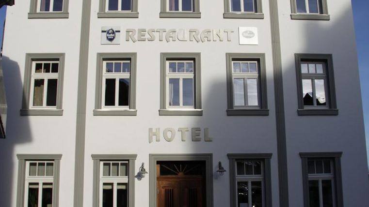 Ein modernes Gebäude mit dem Schriftzug "Hotel" und "Restaurant" an der Fassade. Die Fenster sind hell und einladend gestaltet.